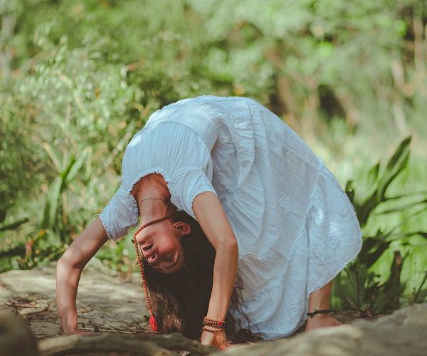 Woman in a peaceful yoga pose in a serene green environment.
