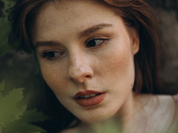 Woman meditating outdoors with a calm expression on her face.